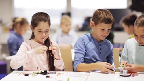 Smiling elementary students triumphantly build robots in robotics school lesson