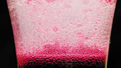 macro shot of sparkling red bubbles moving up in a glass with bright background