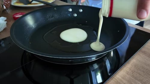 Pouring Pancake Batter onto a Pan Cooking Indoors