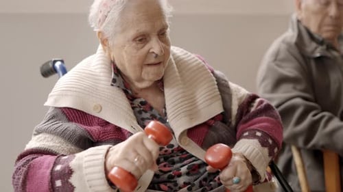 Old Woman Exercising with Dumbbells Sitting on a Nursing Home