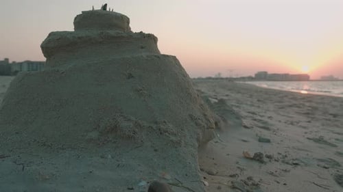Sandcastle on beach with ocean at sunset