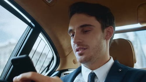 Happy Man Uses Smartphone in Car Backseat