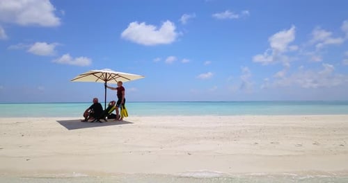 Pan around three men relaxing on beautiful Maldives sandbar, 4k