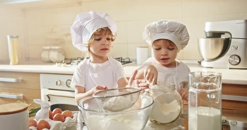 Two Toddlers in Chef Hats Cooking and Sharing Recipes in a Kitchen