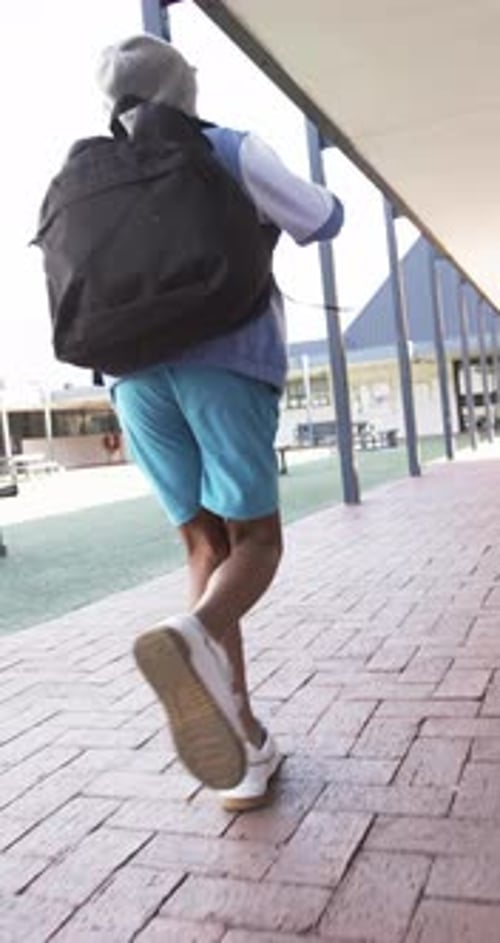 Vertical video: In school, child with backpack walking on campus, heading to class