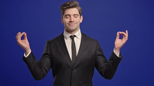 Man Meditating in Suit Against Blue Background