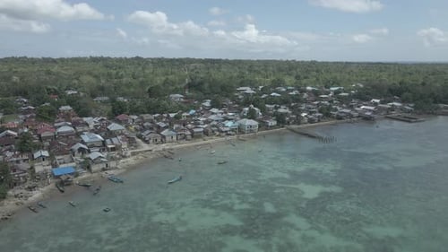 Vue aérienne du village près d'une belle plage avec une petite île en arrière-plan à Moluques, Indonésie