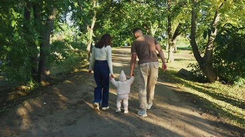 Family Stroll on a Sunny Path Through a Lush Green Park in Autumn