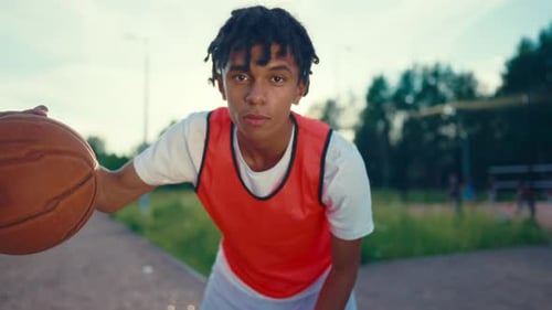 Skilled Young Streetballer Training and Looking at Camera Portrait on Court Basketball Player