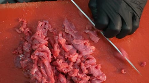 Chef Cuts Raw Meat on a Red Cutting Board