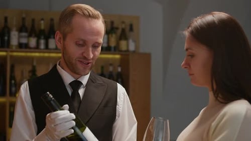Sommelier Helping to Choose Wine to Young Female Customer in Wine Shop