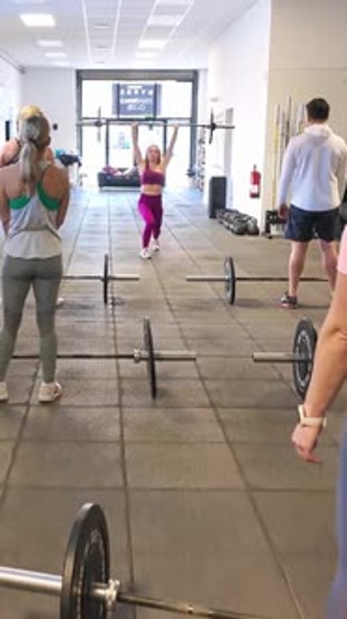 Determined Athlete Lifting a Barbell in a Gym Group Class