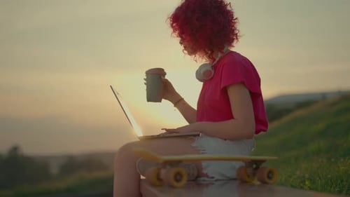 Young Adult Working on Laptop Outdoors at Sunset