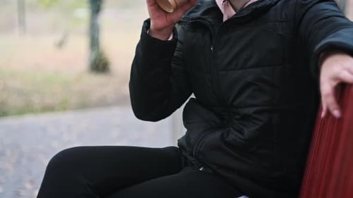 Young Woman Drinks Coffee From Paper Cup on Bench in an Autumn Park