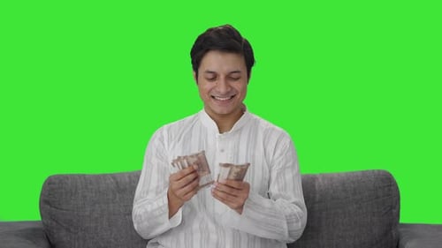 Happy Indian man counting money Green screen