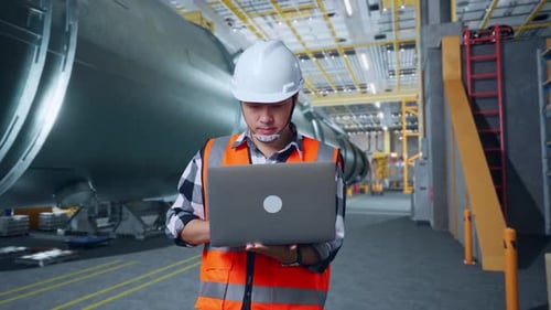 Asian Male Engineer Working On A Laptop In Pipe Manufacturing Factory
