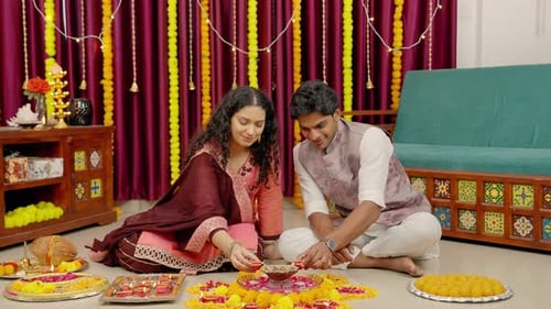 Young Couple Lighting Diwali Oil Lamps Together