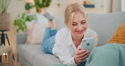 Smiling Woman Lies on Sofa Using Smartphone