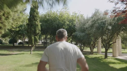 Adult Man Running Through Park on Sunny Day