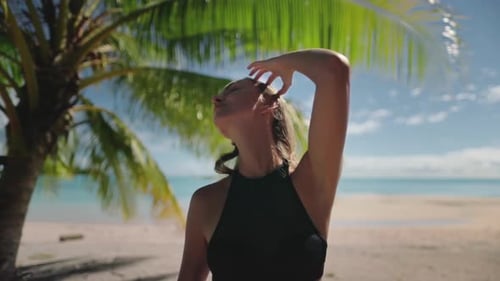 Young Woman Relaxing Under Palm Tree on Tropical Beach