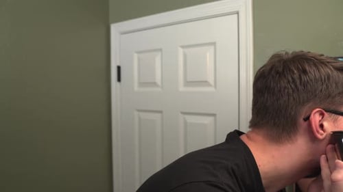 Man Trimming Beard in Bathroom with Electric Razor