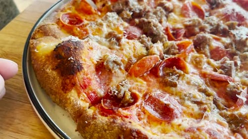 Primer plano de pizza de salchichas y queso pepperoni en un plato