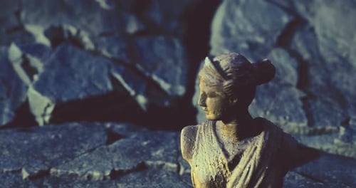 Die detaillierte Büstenskulptur hebt sich vor dunklem felsigem Hintergrund ab