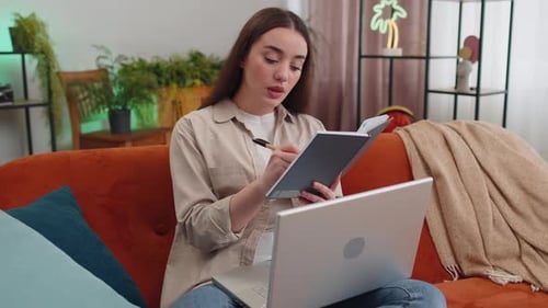 Woman Uses Laptop and Notebook on Couch