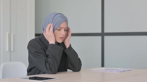 Woman in Hijab Experiencing Headache at Desk
