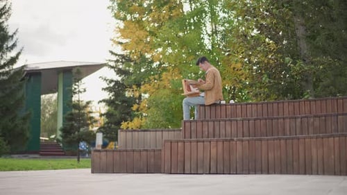 Casual Artist Capturing Scene on Notebook Amidst Urban Park Environment Person Creating Artwork on