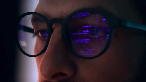 Close-up of Man with Coding Reflection in Glasses