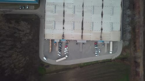 Top view, drone shot, of a cargo truck parking next to industrial buildings