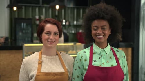 Two young diverse workers portrait standing inside coffee shop. Local business concept of female