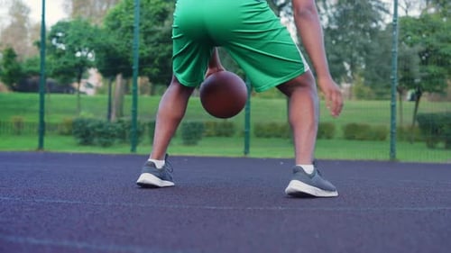 Rear View of Black Male Player Practicing Basketball Handling Skill Outdoors