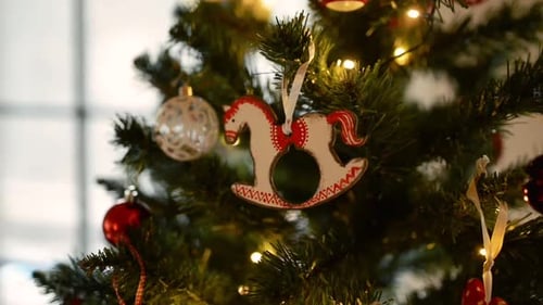 Wooden horse ornament hanging on a beautiful christmas tree branch inside a home