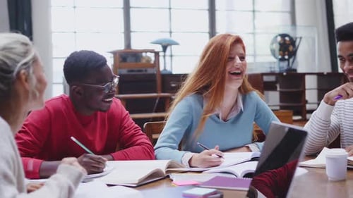 Glückliche multiethnische College-Studenten, die zusammen lernen und in der Universitätsbibliothek lachen