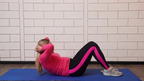 Frau trainiert auf der Matte im hellen Fitness-Outfit