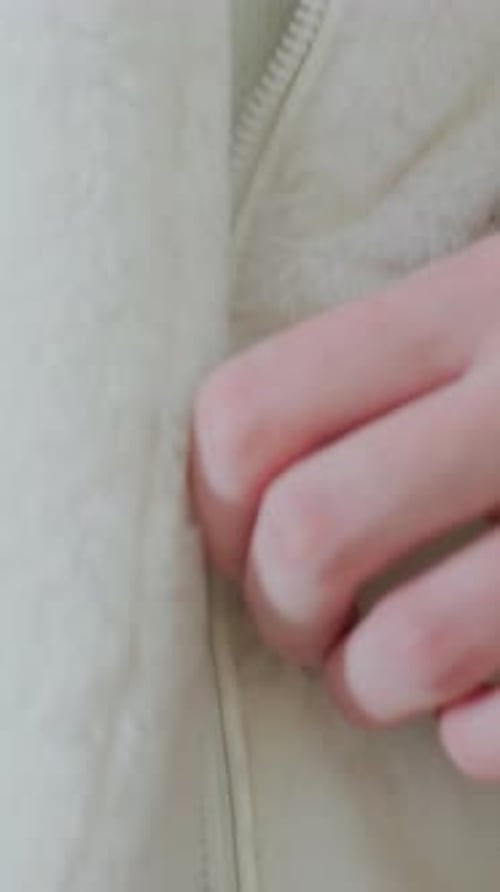 Close Up Zipping Up A Cream Colored Jacket