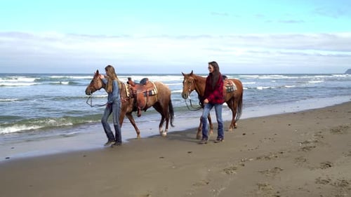 Two women enjoying a horseback ride on a beautiful beach coastline