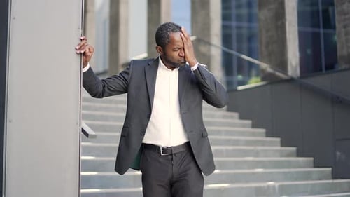 Mature African American businessman in suit suffering from tension and headache while standing