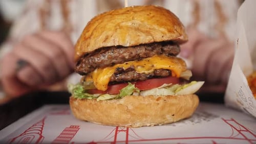 Close Up Hands Takes Cheeseburger Big Appetizing Burger with Meat Patty Onion Vegetables Cheese