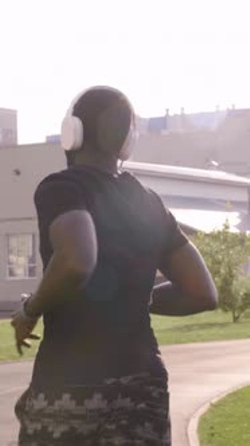 Man Runs Wearing Headphones in Urban Environment