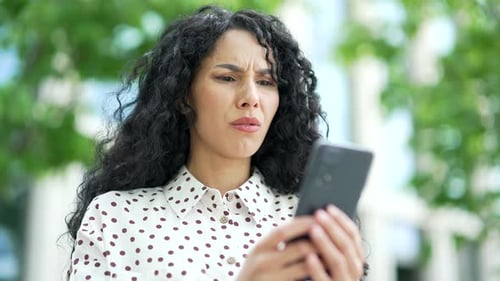 Close up. Disappointed young female employee read bad news on smartphone while standing