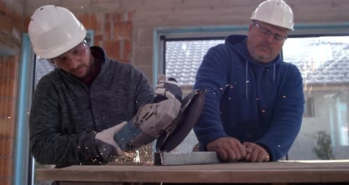 Construction Workers Cutting Metal with an Angle Grinder