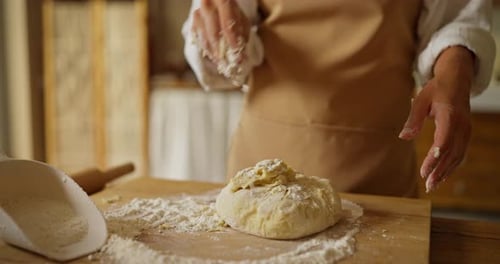 Confident Girl Baker in a White Shirt and Beige Apron Delivers Dough with Flour While Kneading and