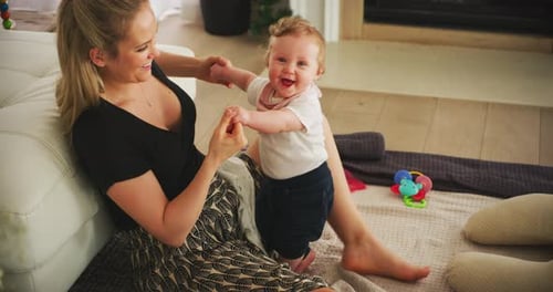 Woman Helping Infant Learn to Walk at Home