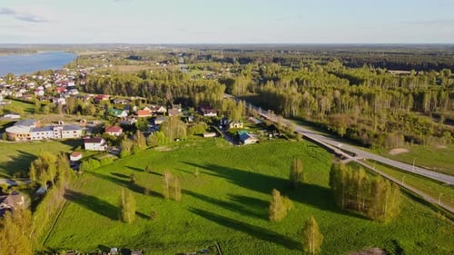Slow drone flyover captures Katlakalns houses, Daugmale road, and spring fields, Daugava River