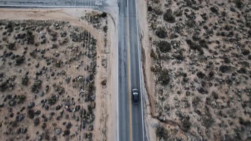 Aerial Drone Shot of a Car Driving on a Long Isolated Road in the Desert