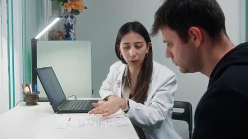Doctor Explains Paperwork to Male Patient at Office