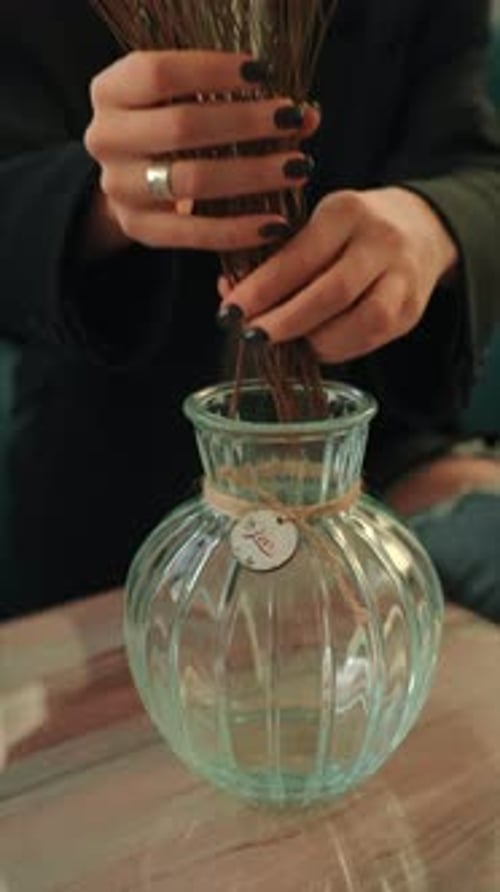 Woman Arranges Flora in Vase on Marble Table